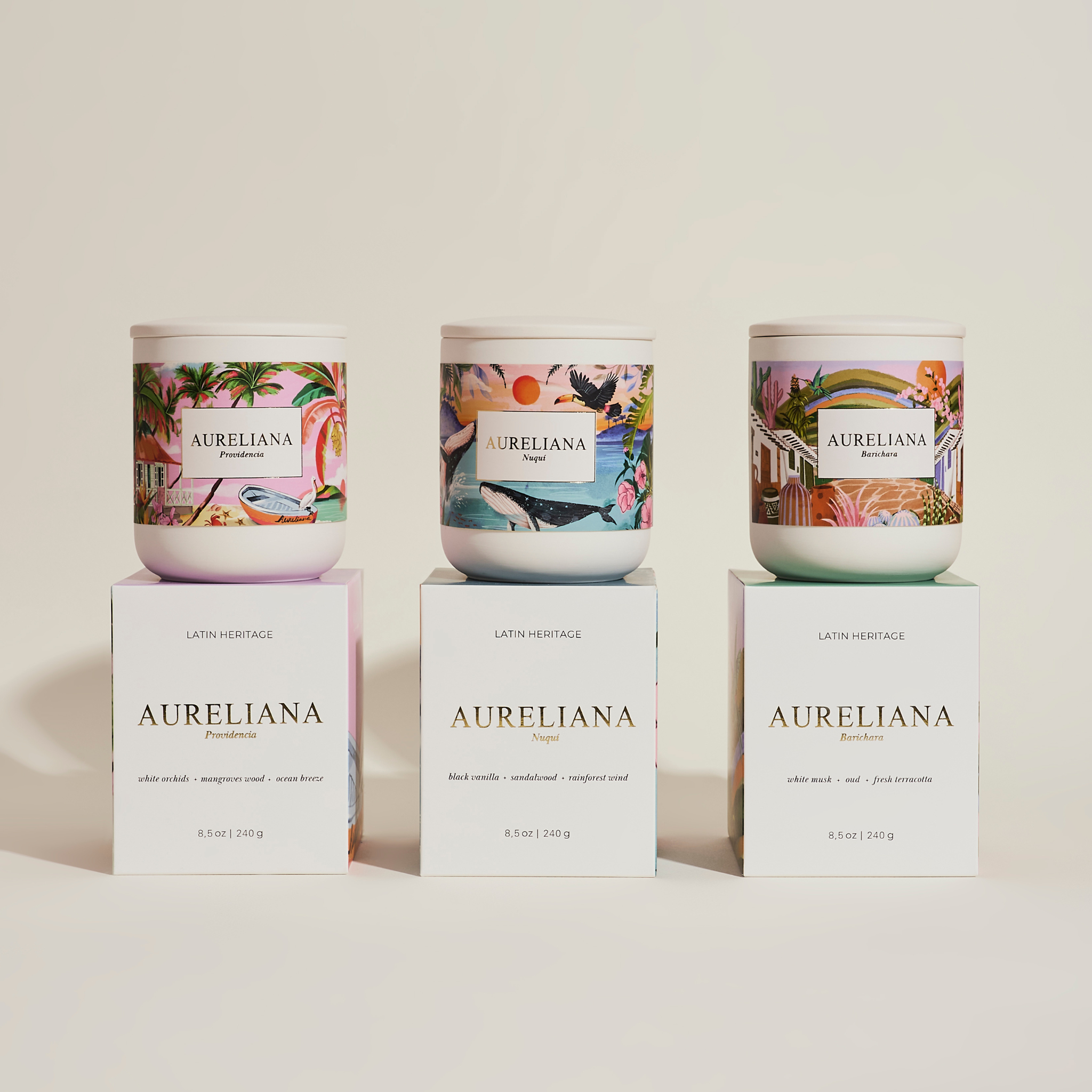 Three Aureliana candles with decorative labels on a light beige background