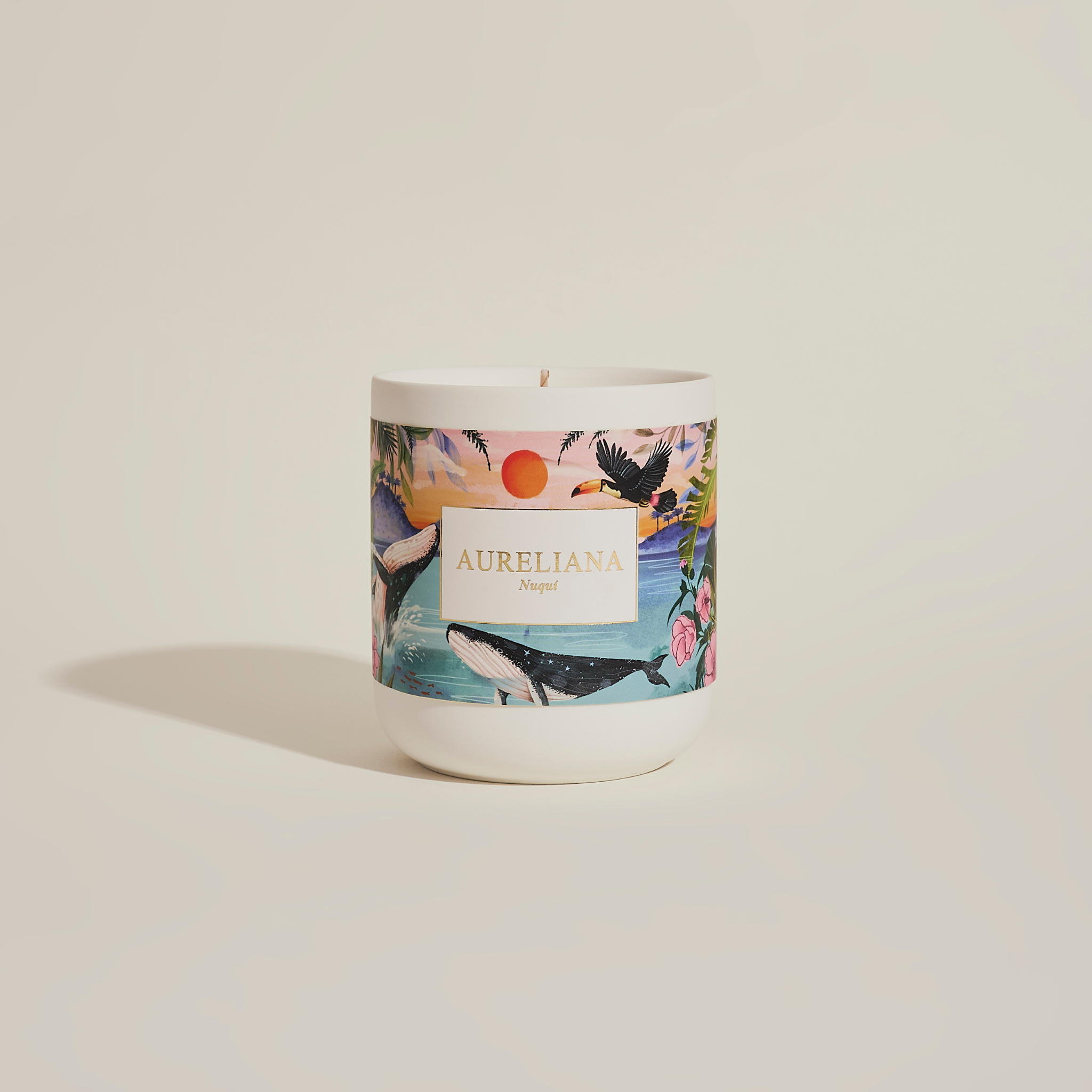 Candle with a colorful label featuring nature-themed design on a beige background