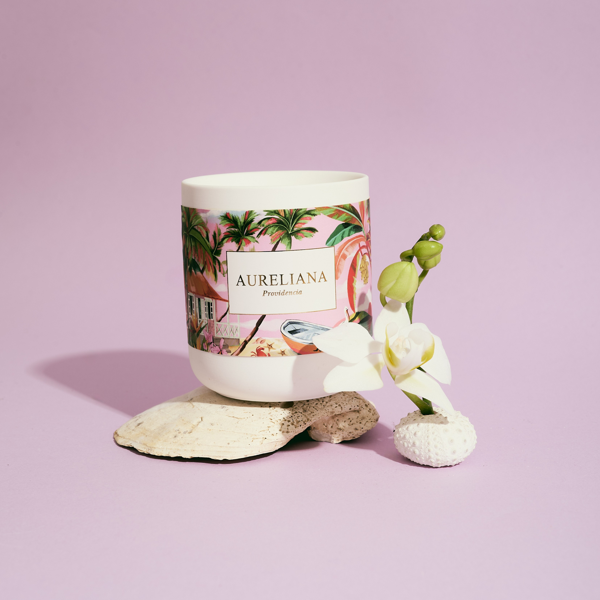 Candle with floral design and 'Aureliana' branding on a pink background
